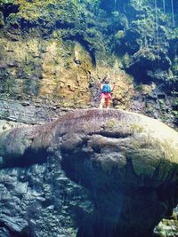 Full length of young woman on rock against trees