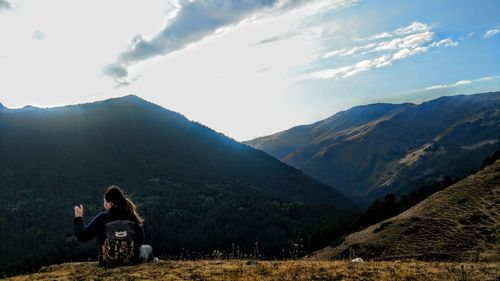 Rear view of woman photographing mountain against sky