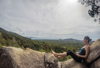 Woman sitting on chair by mountain against sky