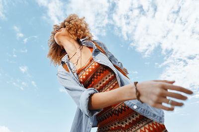 Rear view of woman holding umbrella against sky