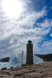 Lighthouse by sea against sky