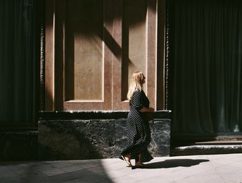 Woman walking by road by building