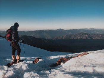 Rear view of person on snowcapped mountain against sky