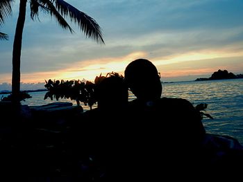 Rear view of silhouette people on beach at sunset