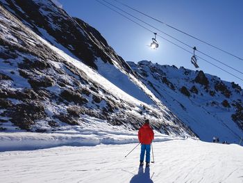 Rear view of person walking on snow covered mountain