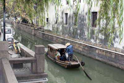 Rear view of man sailing boat in canal