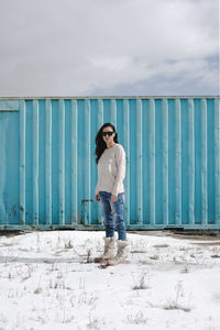 Portrait of woman standing against blue metallic container