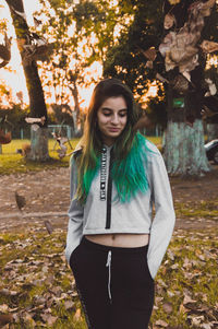 Portrait of smiling young woman standing in park during autumn