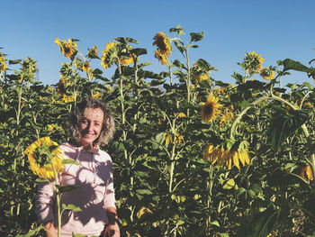 Young woman standing against plants and trees against sky