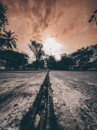 Surface level of railroad tracks against sky during sunset