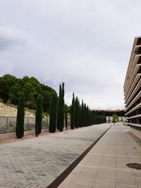 View of footpath in park against cloudy sky