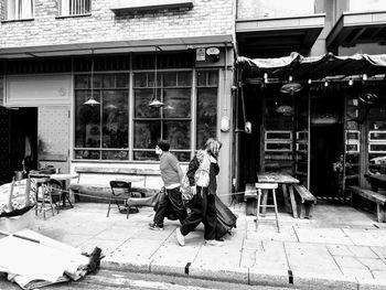 People sitting on sidewalk by street against buildings in city