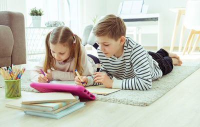 Smiling kids using digital tablet while sitting at home