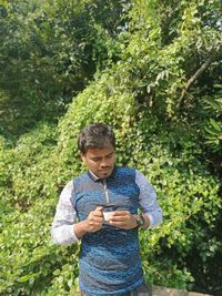 Close-up of man holding camera lens against plant