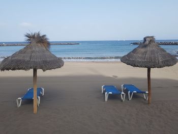 Deck chairs on beach against clear sky