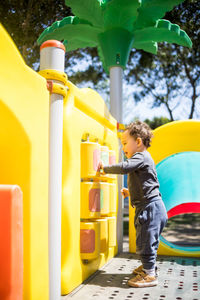 Toddler boy plays on colorful children playground at the park.