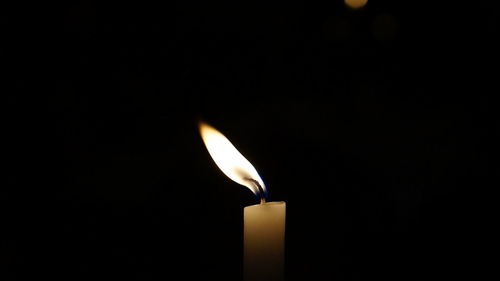 Close-up of lit candle in darkroom