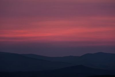 Scenic view of silhouette mountains against romantic sky at sunset