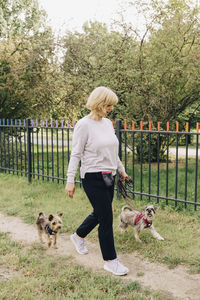 Mature woman walking cute dogs in public park