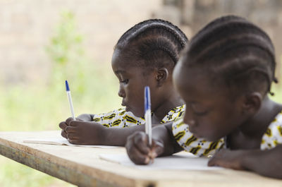 Close-up of girls writing in book