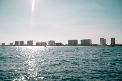 Sea by buildings against sky