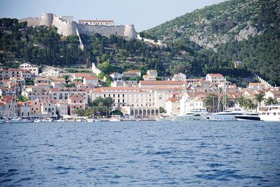 Buildings by sea against mountain in town