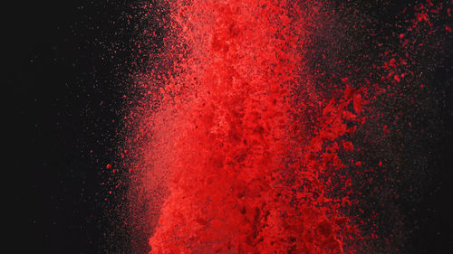 Close-up of powder paints exploding against black background