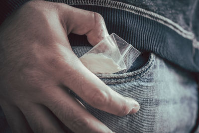 Close-up of man putting cocaine packet in pocket