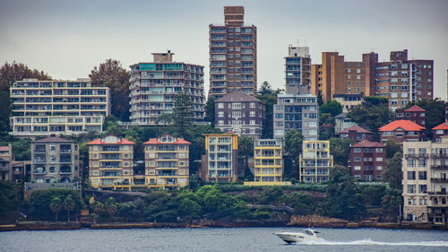 Buildings by river against sky in city