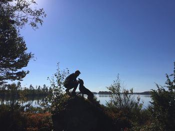 Low angle view of silhouette man jumping against clear sky