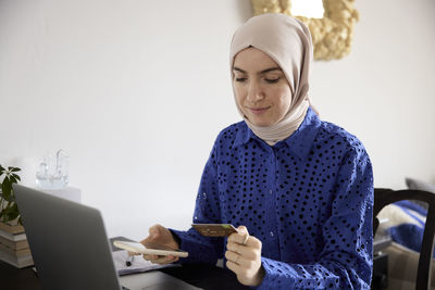 Woman in headscarf paying bills online at home