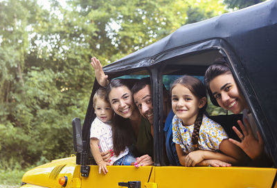 Portrait of people waving while peeking from car window