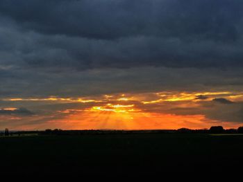 Scenic view of silhouette field against sky at sunset