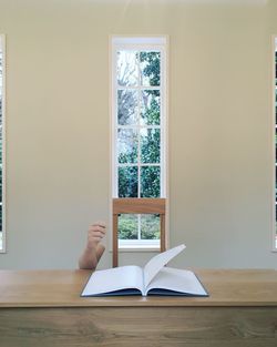 Person reading book against wall at home