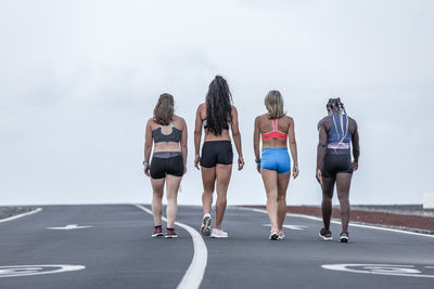 Rear view of women walking against sky