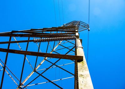 Low angle view of electricity pylon against blue sky 