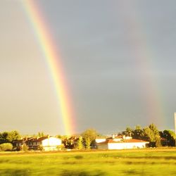 Rainbow over houses against sky