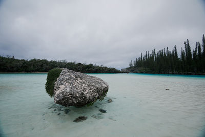 View of rock in lake against sky