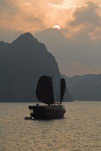 Sailboat sailing on sea against sky during sunset