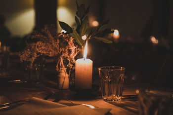 Illuminated candles on dining table in darkroom