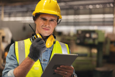 In the background, an engineer is using a tablet while working in a factory warehouse.