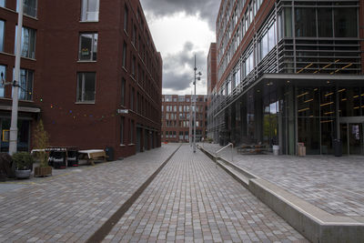 Empty street amidst buildings in city against sky