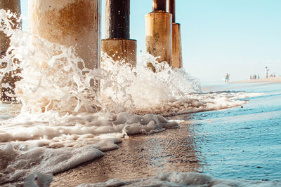 Sea waves splashing on beach against sky