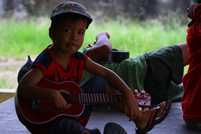 Portrait of boy playing guitar while sitting on floor