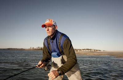 Man fishing at sea against clear sky