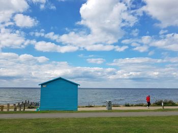 Man jogging by beach against sky