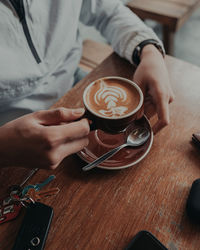 Midsection of woman holding coffee cup on table