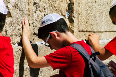 Portrait of man holding hat against wall