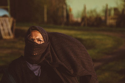 Portrait of woman wearing eyeglasses and scarf on face outdoors