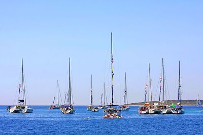 Sailboats sailing in sea against clear blue sky